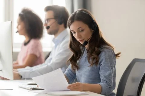 Customer support phone operator sitting at workplace holds read document Stock Photos