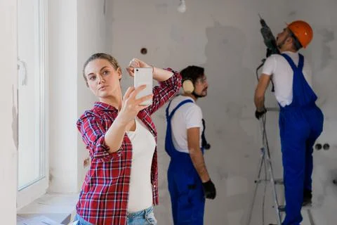 Customer takes a selfie on the background of constructor workers at work Stock-Fotos