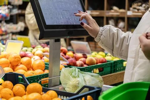 Customer touching digital screen on a produce scale in a supermarket to wei.. Stock Photos