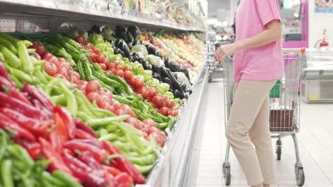 A customer with a trolley in the store chooses vegetables Stock Footage 223647709