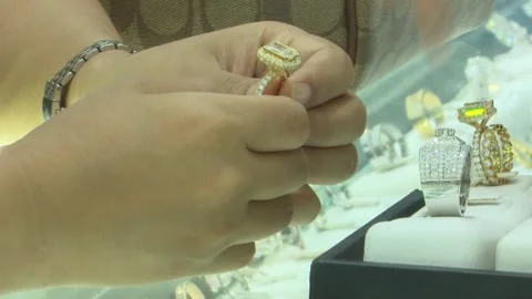 Customer Trying On Gold Diamond Ring At Counter With Handbag Stock Footage 345502555