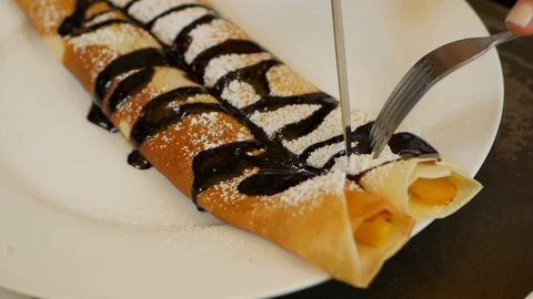 Customer using a fork and knife eat delicious crepes roll with fresh mango Vídeo Stock 117104690