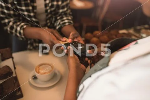 Customer using her credit card to pay for a cappuccino Stock Photos