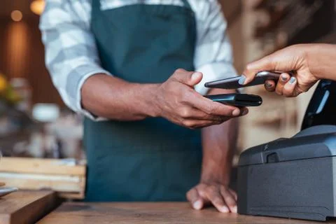 Customer using her smartphone to pay for her cafe purchase Stock Photos