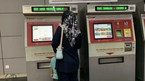 Customer is using LRT train ticket machine at puchong jaya station. Stock Photos