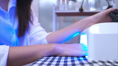 A customer is using a nail dryer after the manicurist coats Stock Footage 278743061