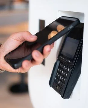 Customer Using Smartphone To Contactless Payment In Shop Stock Photos