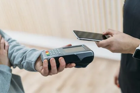 Customer using smartphone nfc technology to make a purchase at a store Stock Photos