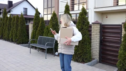 Customer using smartphone while waiting for delivery near cardboard boxes Stock Footage 330385983