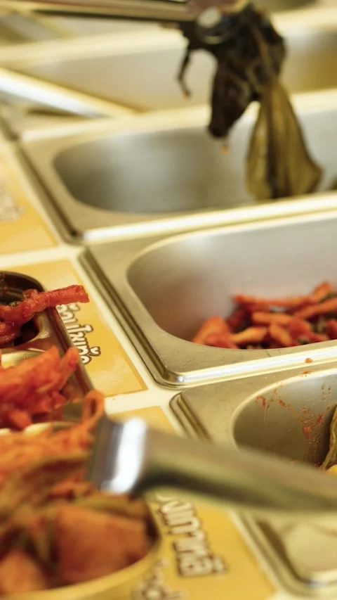 Customer Using Tongs to Select Korean Side Dishes at Buffet Stock-Footage 340194543
