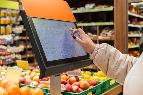 Customer using a touchscreen price scale at a fruit section in a modern gro.. Stock Photos