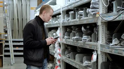 Customer utilizes smartphone app to compare prices and availability of materials Stock Photos