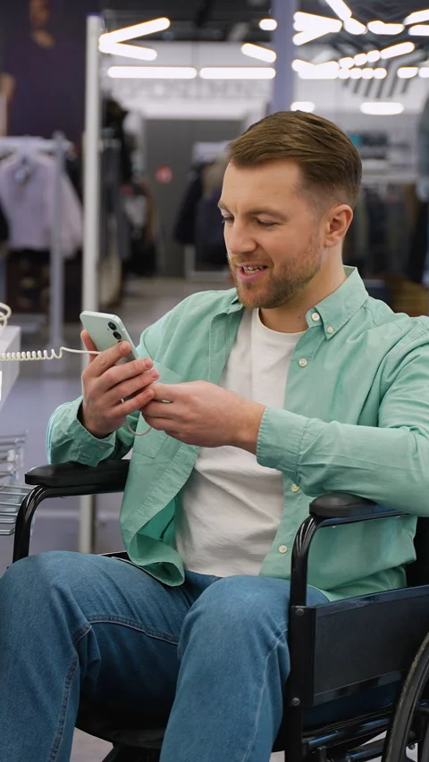 Customer in wheelchair testing smartphone in electronics store Stock Footage 311941185
