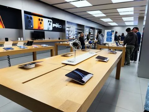 Customers explore latest Apple gadgets in a bright electronics store with t.. Stock Photos
