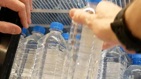 A customer's hand taking a bottle of potable water from a store fridge Vidéo 331275316