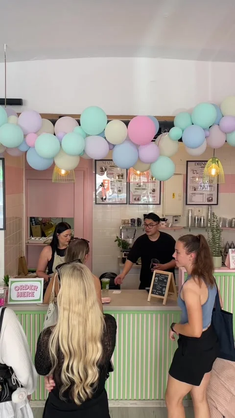 Customers ordering drinks at pastel decorated cafe counter with barista, with Видео 344584949