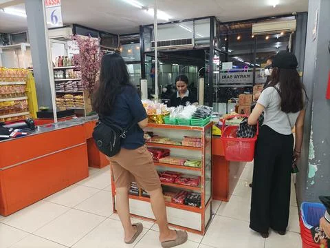 Customers queue at a checkout counter in a local Indonesian grocery store Stock Photos