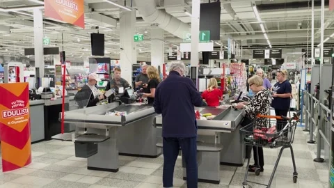 Customers queue at the checkout of a K-Supermarket while a cashier scans Stock Footage 342914653