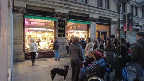Customers queue up in front of a historic delicatessen store in the old town Stock Footage 296069174
