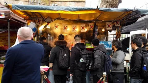 Customers queue at a stall at a Food Market on Tottenham Court Road, London Stock Footage 100908490
