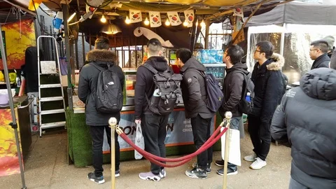 Customers queue at a stall at a Food Market on Tottenham Court Road, London, UK Stock Footage 101330663