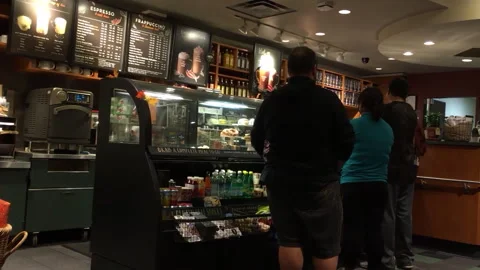 Customers queuing at a busy urban coffee shop counter with seasonal displays Stock Footage 346636288