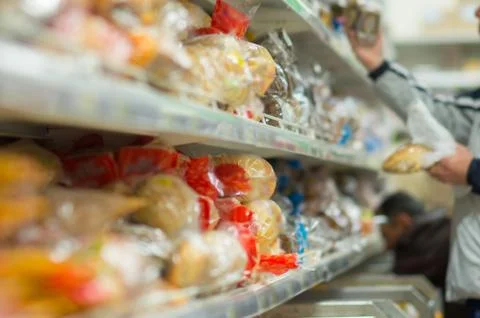 Customers select variety of bread on shelfs in supermarket Stock Photos