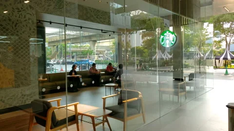 Customers Sitting Inside Modern Starbucks Coffee Store With Glass Facade in City Stock Footage 130771029