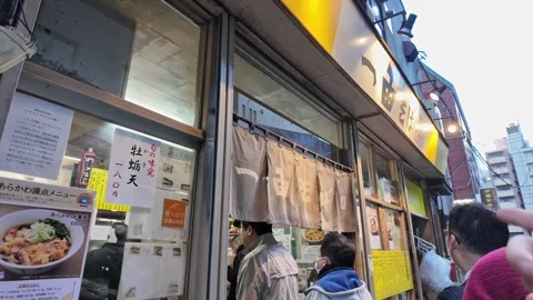 Customers wait in line outside a bustling Japanese ramen shop. Stock Footage 346011779