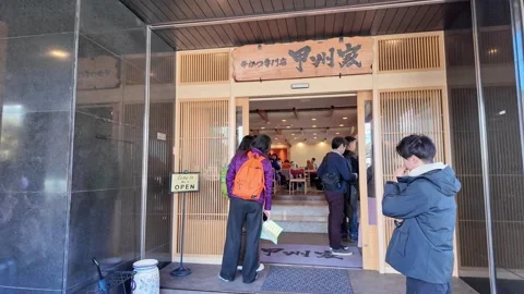 Customers wait in line outside a Japanese restaurant entrance. Stock Footage 346011841