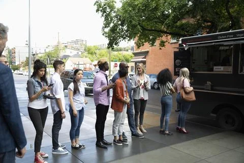 Customers waiting in queue outside food truck 스톡 사진
