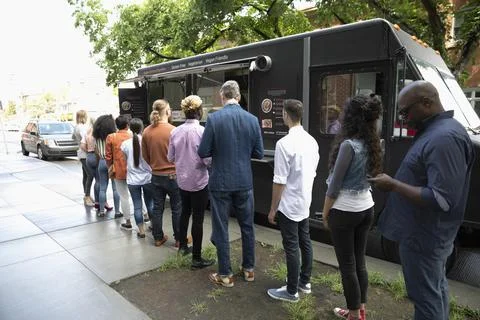Customers waiting in queue outside food truck Stock Photos