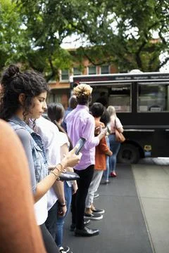 Customers waiting in queue outside food truck Foto stock