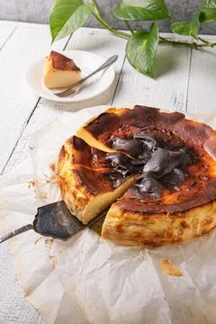 Cut basque burnt cheesecake with silver spatula at home kitchen Stock Photos