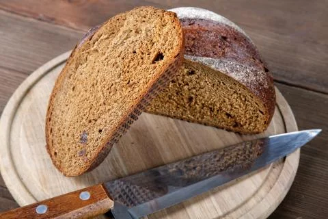 The cut black bread on a wooden table Stock Photos