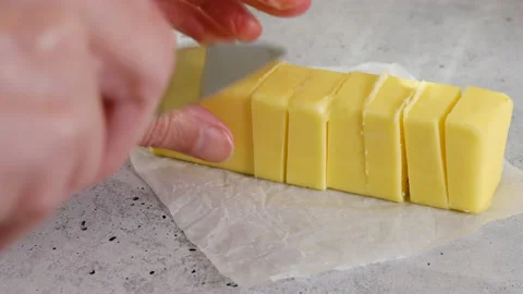 Cut block of butter on the kitchen table. Woman cuts butter with knife. Stock Footage 228707381