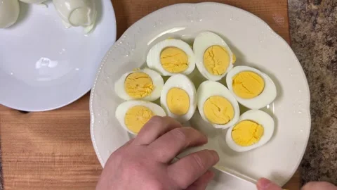 Cut boiled chicken eggs in half on a plate with a knife. 库存影片 301332346