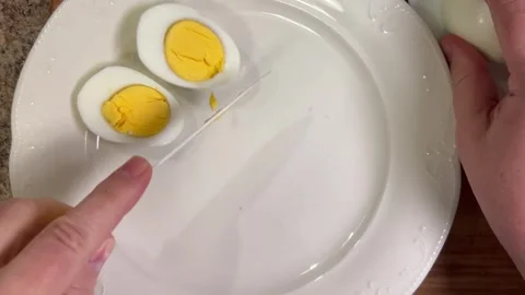 Cut boiled chicken eggs in half on a plate with a knife. Top view. Stock Footage 301891310