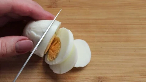 Cut boiled eggs into rings with a knife on a wooden board. Stock Footage 237232482