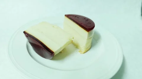 A cut caramel custard pudding cake halved on a white plate. Stock Footage 345338976