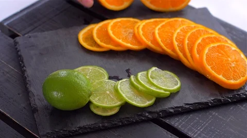 Cut into circles of lime and orange on black stone. Preparation for cocktails Stock Footage 110038019