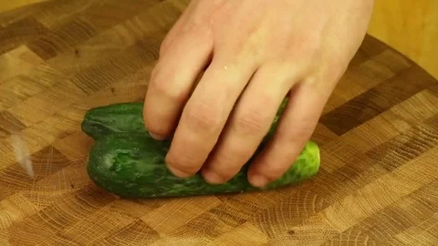 Cut cucumber with a sharp knife on a wooden board Stock Footage 83374285