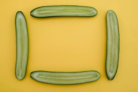Cut cucumbers in half lengthwise in the shape of a rectangle on a yellow back Stock Photos