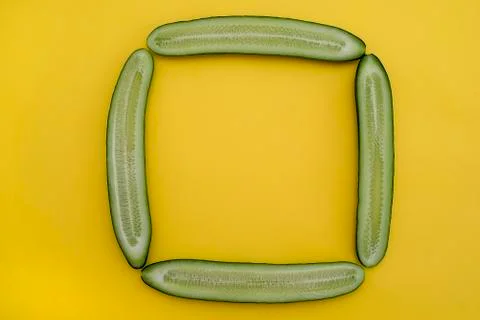Cut cucumbers in half lengthwise in the shape of a square on a yellow backgro Foto stock