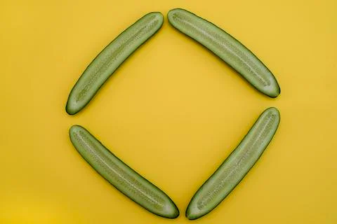 Cut cucumbers in half lengthwise in the shape of a rectangle on a yellow back Stock Photos