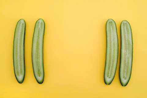Cut cucumbers in half lengthwise at the sides, yellow background Stock Photos