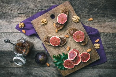 Cut figs, nuts and bread with jam on wooden choppingboard Stock Photos