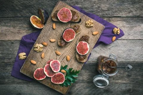 Cut figs, nuts and bread with jam on choppingboard in rustic style Stock Photos