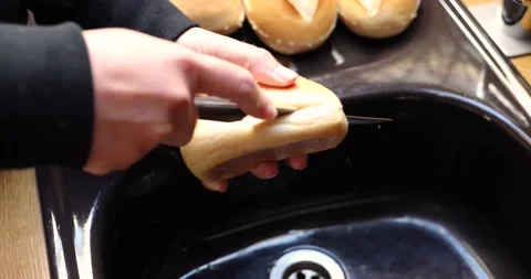 Cut fresh bread with a knife for breakfast Stock Footage 130579763