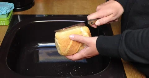 Cut fresh bread with a knife for breakfast Stock Footage 130579876